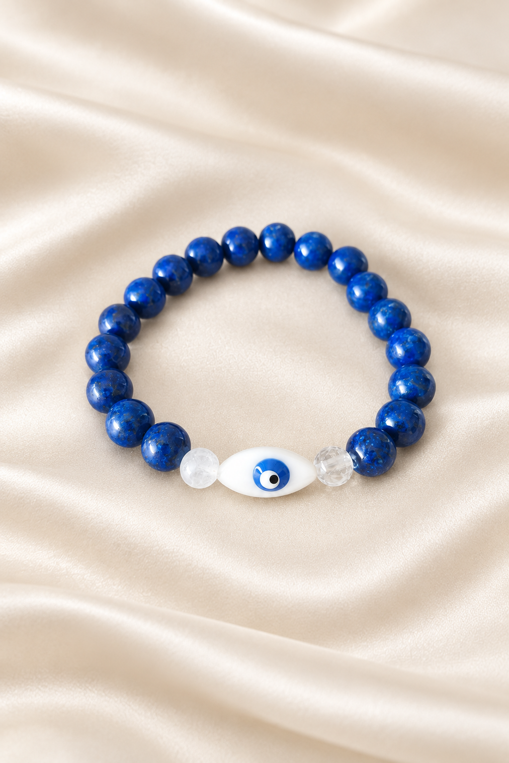 Pulseira azul com detalhe de olho sobre cetim marfim claro
