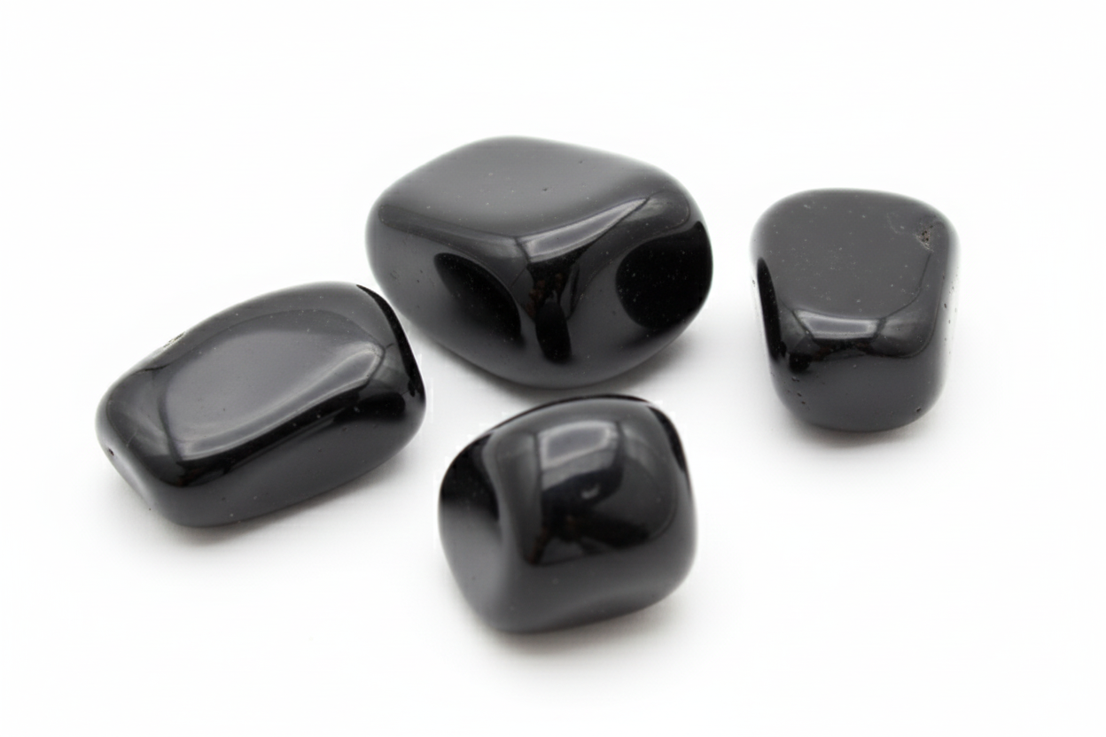 Quatro pedras de obsidiana negra em fundo branco